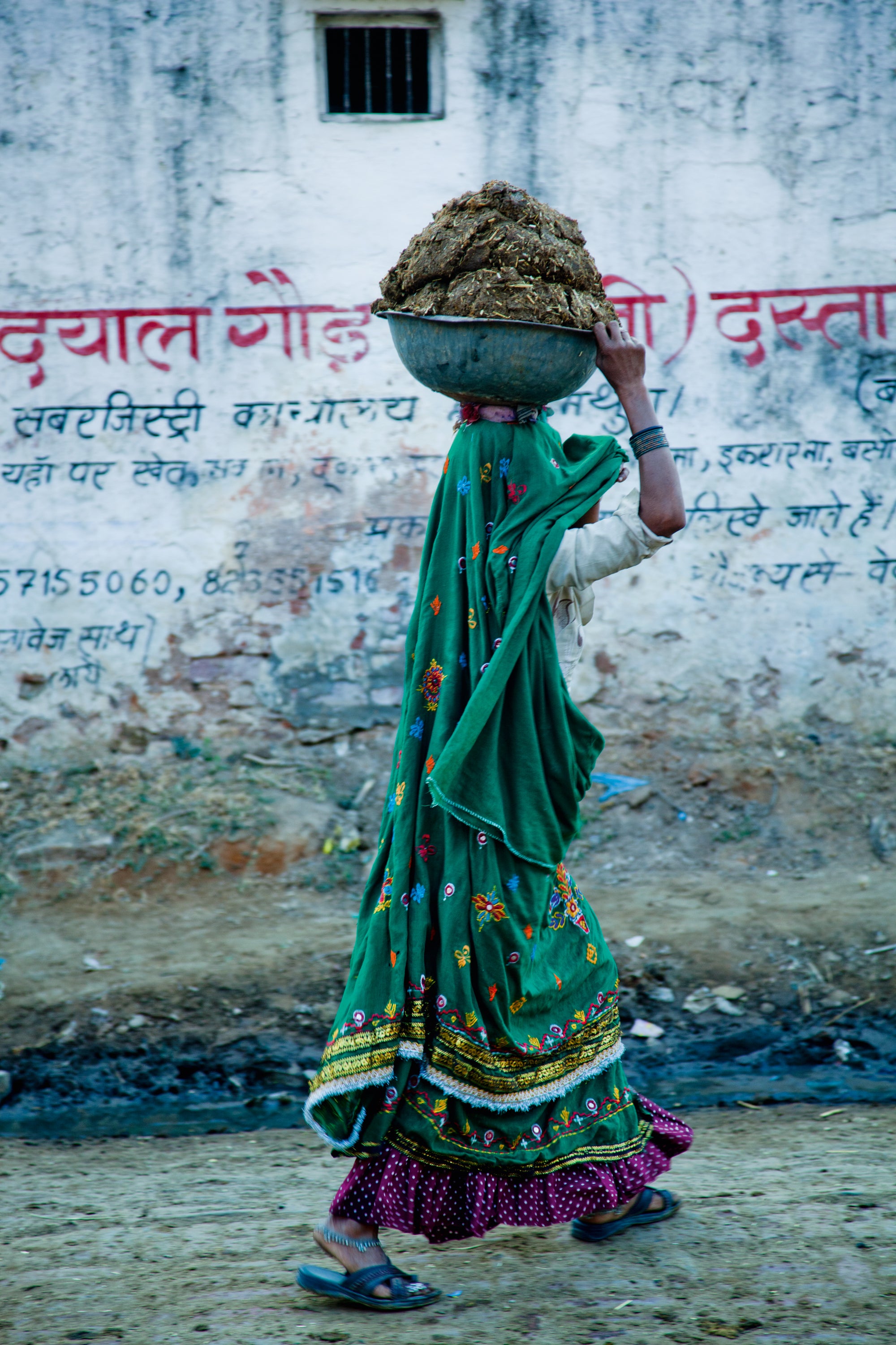 A woman carrying cow dung that she has collected for fuel #2/8
